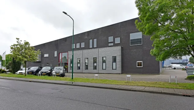 Bedrijfsruimte te huur Veenendaal aan de Newtonstraat 3 met een langgerekt modern bedrijfspand in donkere baksteen en metalen gevelbekleding, grote raampartijen op twee bouwlagen, parkeerplaatsen voor de deur en directe ligging aan de openbare weg op bedrijventerrein De Compagnie nabij de A12