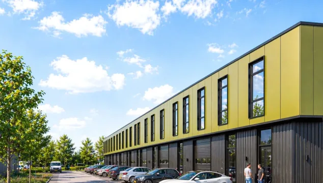 Realistische impressie van een bedrijfspand in Heinenoord met moderne bedrijfsunits, parkeerplaatsen voor de deur, bomen langs het terrein, een bedrijfsbus en twee personen bij de entree onder een heldere blauwe lucht.