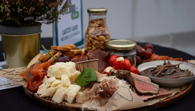 Luxe borrelplank met kaas, vleeswaren, noten, tomaatjes, druiven en brood tijdens het bouwfeest van het bedrijfspand in Arnhem aan de Overmaat, geserveerd op de bouwlocatie voor ondernemers en betrokken partijen.