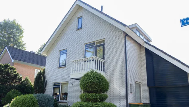 Voorgevel met lichte bakstenen, donkere kozijnen en een wit balkon van de woning die u aan de Valreep in Veenendaal kunt kopen.