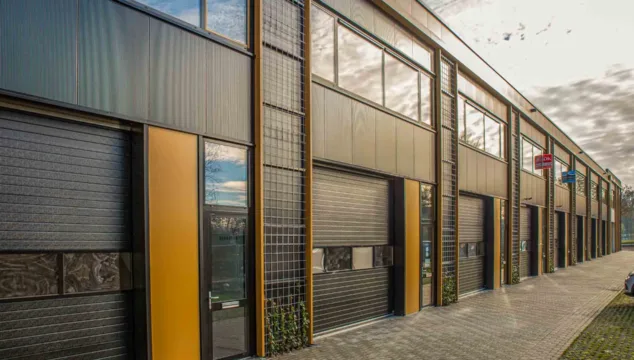 Rij moderne kleine bedrijfsruimtes met grote ramen en overheaddeuren. Deze nieuwbouwpanden tonen de groeiende vraag naar compacte, flexibele bedrijfsunits.