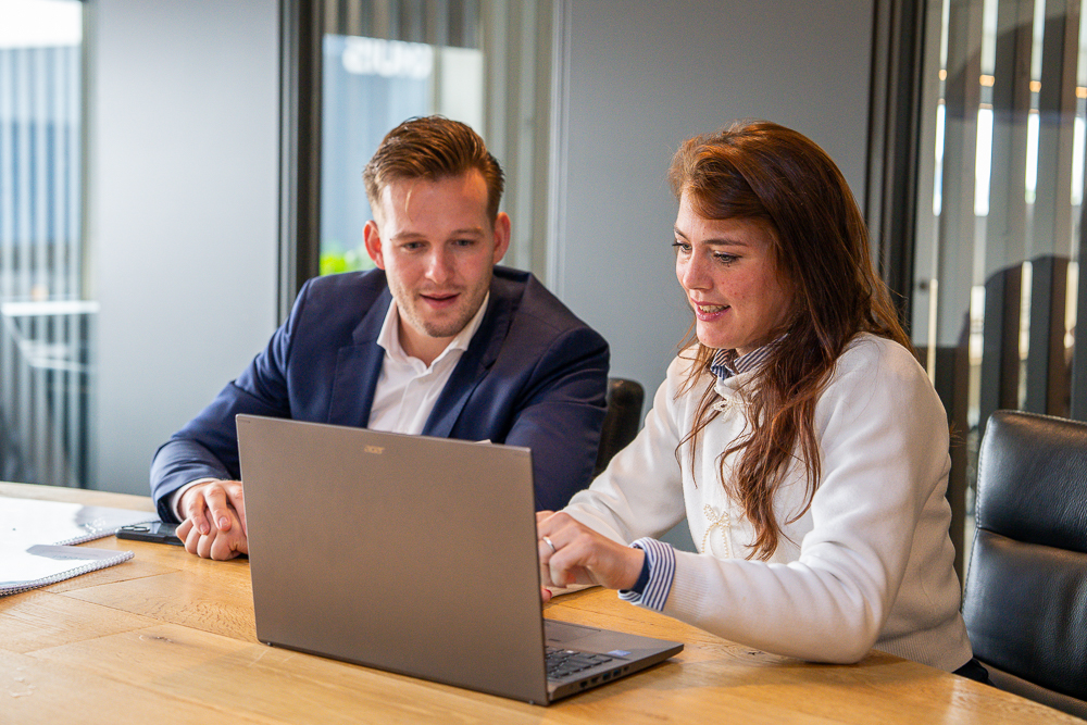 Professioneel overlegmoment door twee adviseurs van Van der Meijden Vastgoed aan tafel in een moderne kantooromgeving, samen werkend aan een laptop en documenten. Overleggend over een bedrijfsruimte dat te huur staat in Veenendaal.