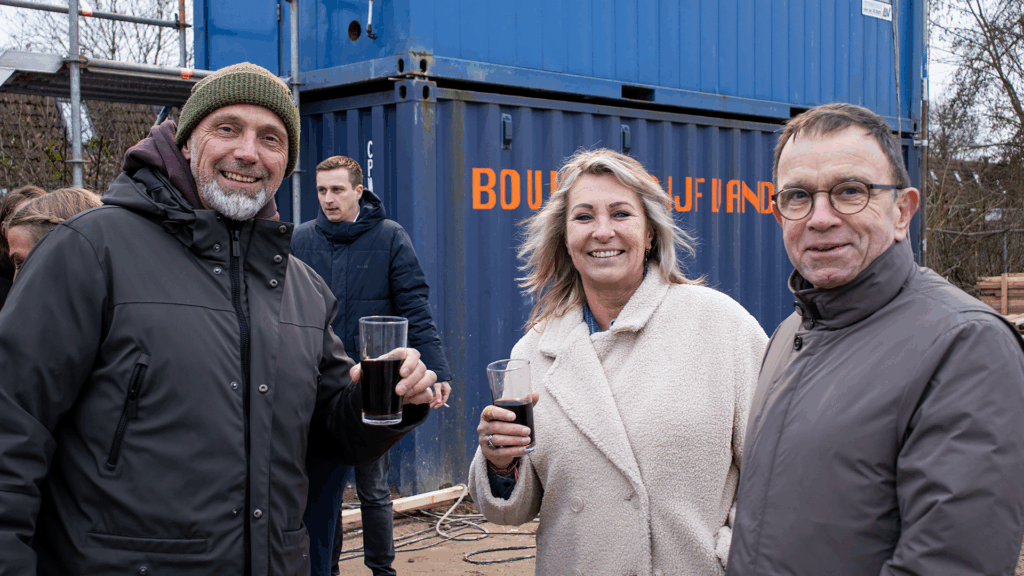 Sfeerbeeld van het bouwfeest bij het bedrijfspand in Arnhem aan de Overmaat, waar ondernemers en betrokken partijen samenkomen op de bouwplaats en met elkaar in gesprek zijn over de voortgang van het project, midden in het nog in aanbouw zijnde pand.