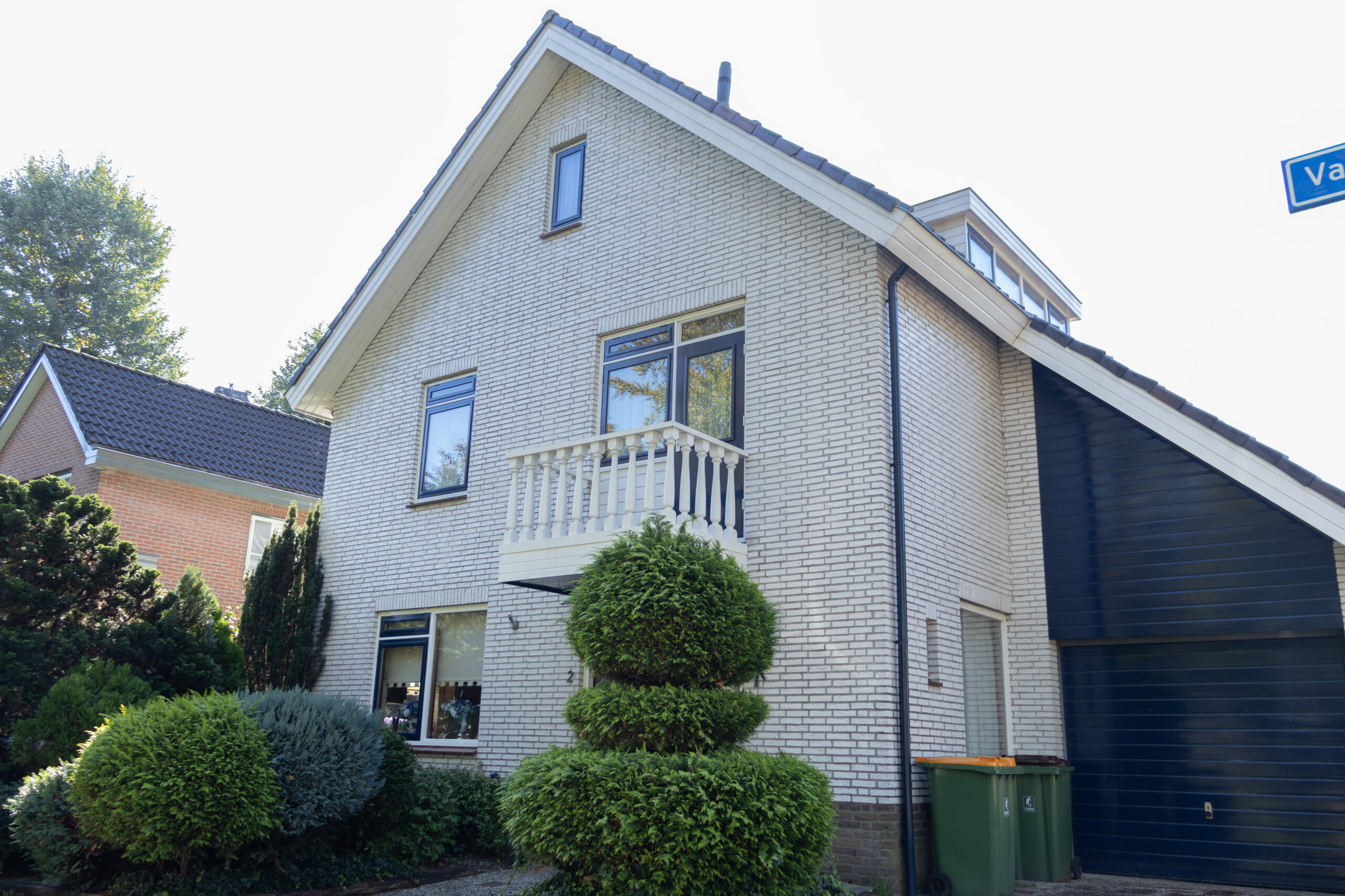 Voorgevel met lichte bakstenen, donkere kozijnen en een wit balkon van de woning die u aan de Valreep in Veenendaal kunt kopen.