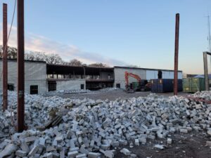 Sloopfase met stapels witte stenen en graafmachine: Start van de bouwfase voor bedrijfspand Oudenbosch fase 1, sloop van bestaande bebouwing nabij Breda.