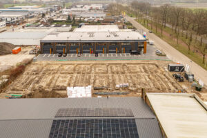 Luchtfoto van het bouwterrein van fase II van bedrijfspand Oudenbosch, met op de achtergrond de reeds opgeleverde bedrijfspanden uit fase I.